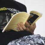 person reading book on black and white textile